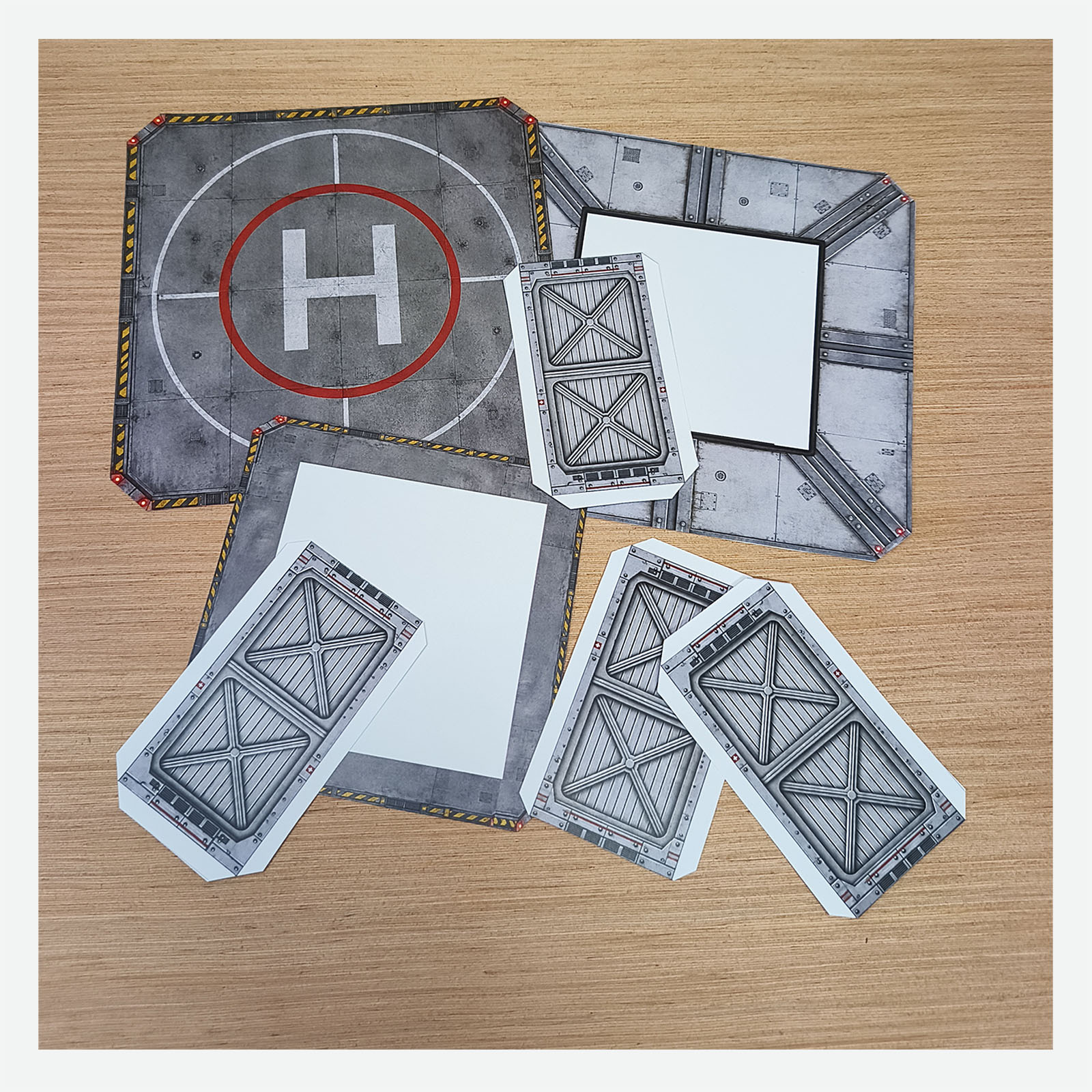 Cut-out pieces from the printable hospital helipad PDF arranged on a wooden desk before assembly